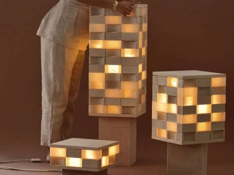 Modular floor and table lamps made of recycled eggshell composite blocks stacked in different heights with warm internal illumination and a person standing by.