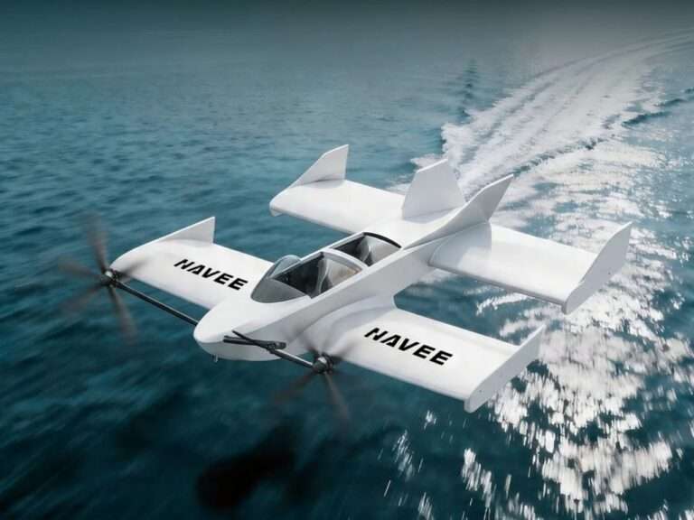 Aerial view of the all-white Navee WaveFly 5X flying watercraft cruising smoothly just above the blue ocean surface, showcasing its unique tandem-wing design and aerodynamic hull.
