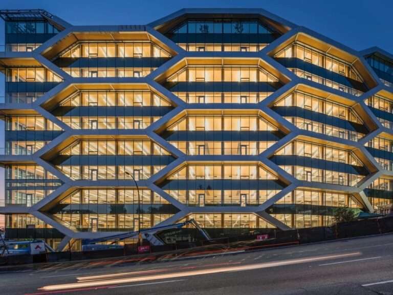 Illuminated honeycomb glulam timber facade of The Hive building in Vancouver at night, showcasing innovative seismic structural design.