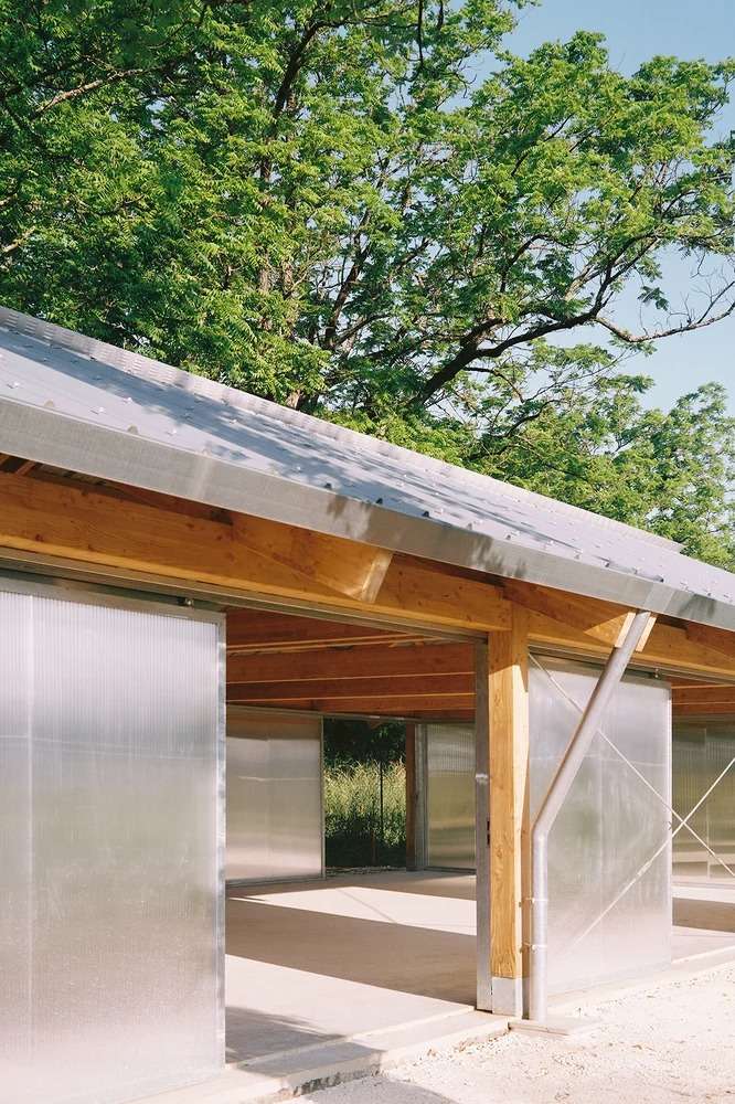 Low-angle exterior detail view showing the metal corrugated roof overhang, timber framing beams, and steel gutters.