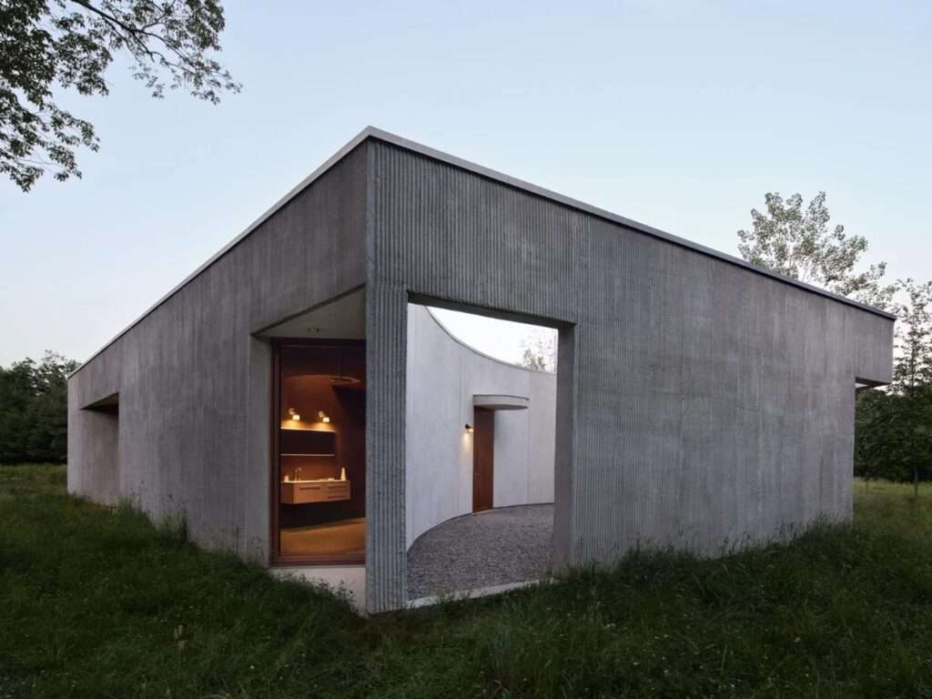 Exterior view of a concrete pavilion featuring contrasting smooth and ribbed plaster textures with geometric cut-outs.