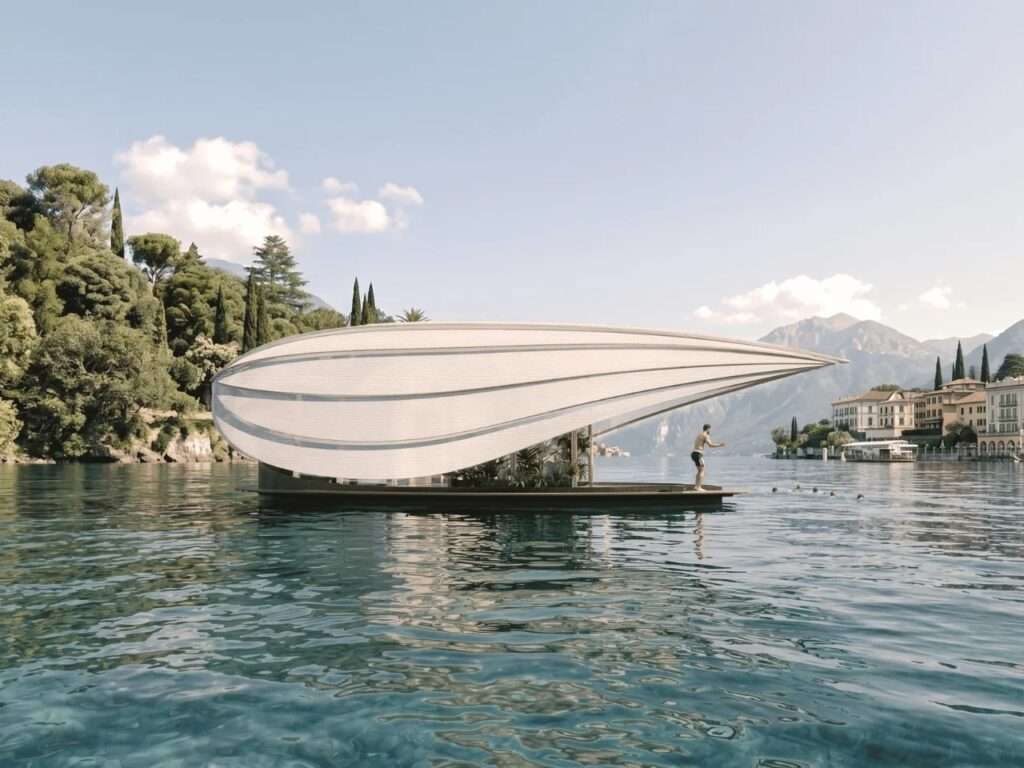 Side view of the minimalist Lucia floating house on Lake Como featuring an organic white fabric roof shell resembling a traditional boat hull with a person standing on the deck.