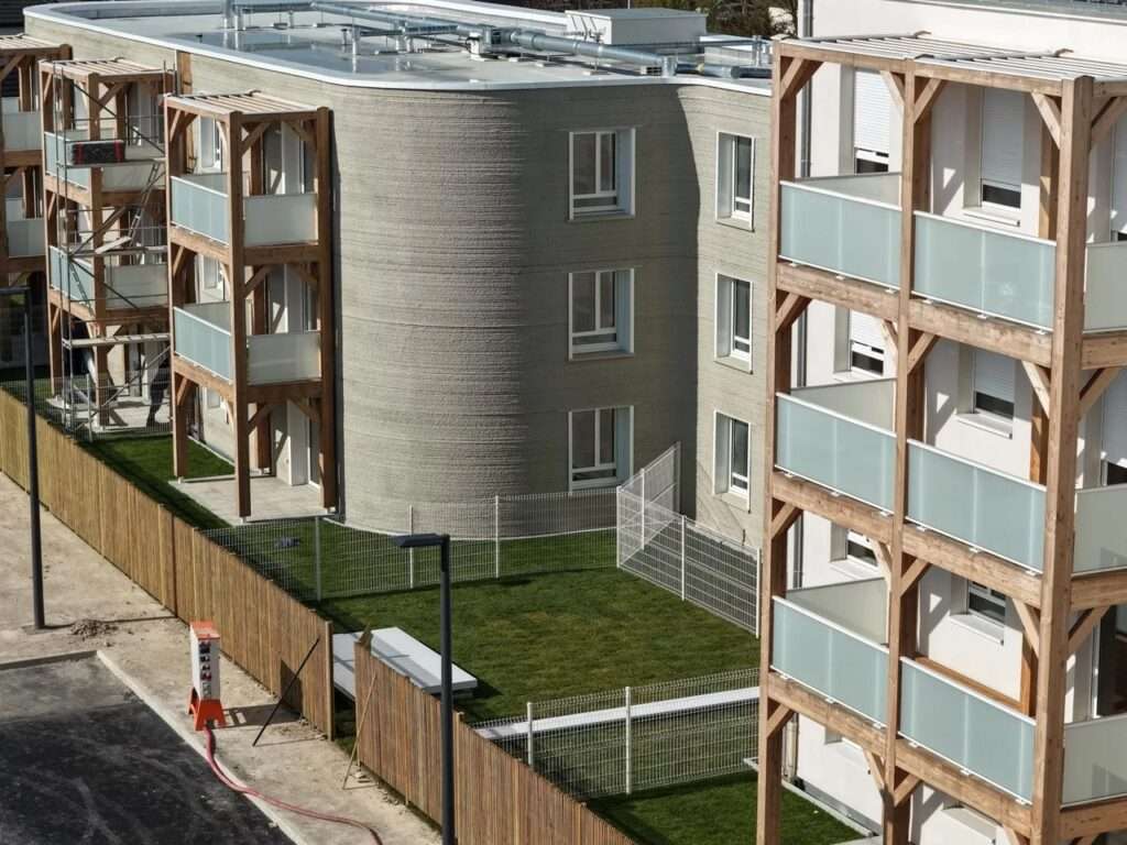 Close-up of the 3D-printed load-bearing concrete walls showing layered texture and integrated multi-story wooden balcony frames.