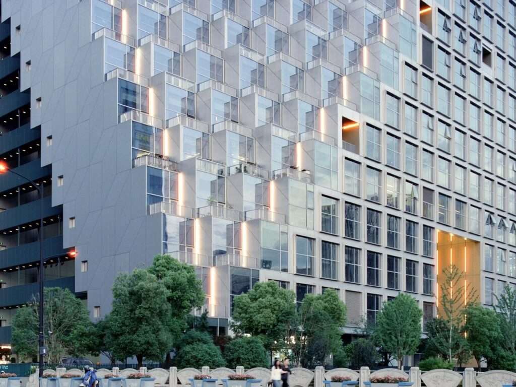 Close-up architectural detail of the stepped glass cubes and terraced balconies on the sloped facade of Hangzhou Prism.