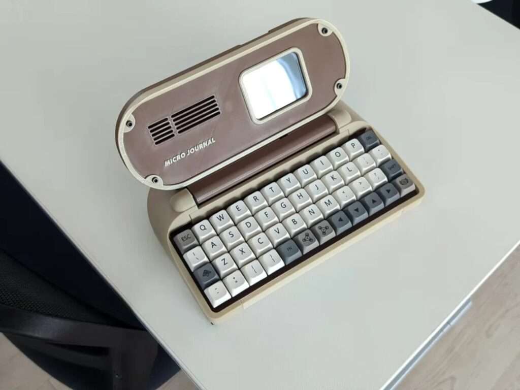 Top-angle view of the Micro Journal Rev.6.1 distraction-free writing device sitting open on a clean white desk surface.