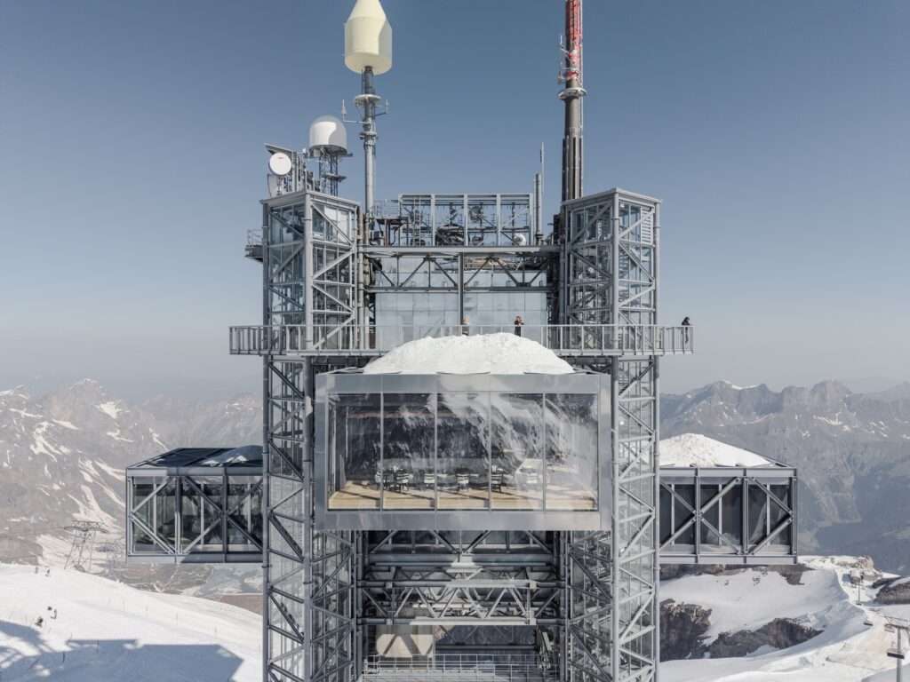 Close-up symmetrical facade view of the Titlis tower showing cantilevered glass restaurant volumes and corner circulation cores.