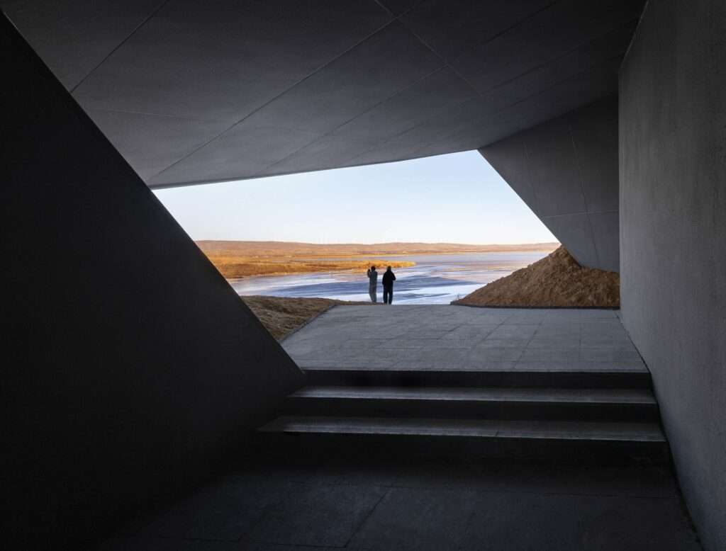People standing on a platform looking at the lake through a large geometric cutout in the Prairie Ark structure.