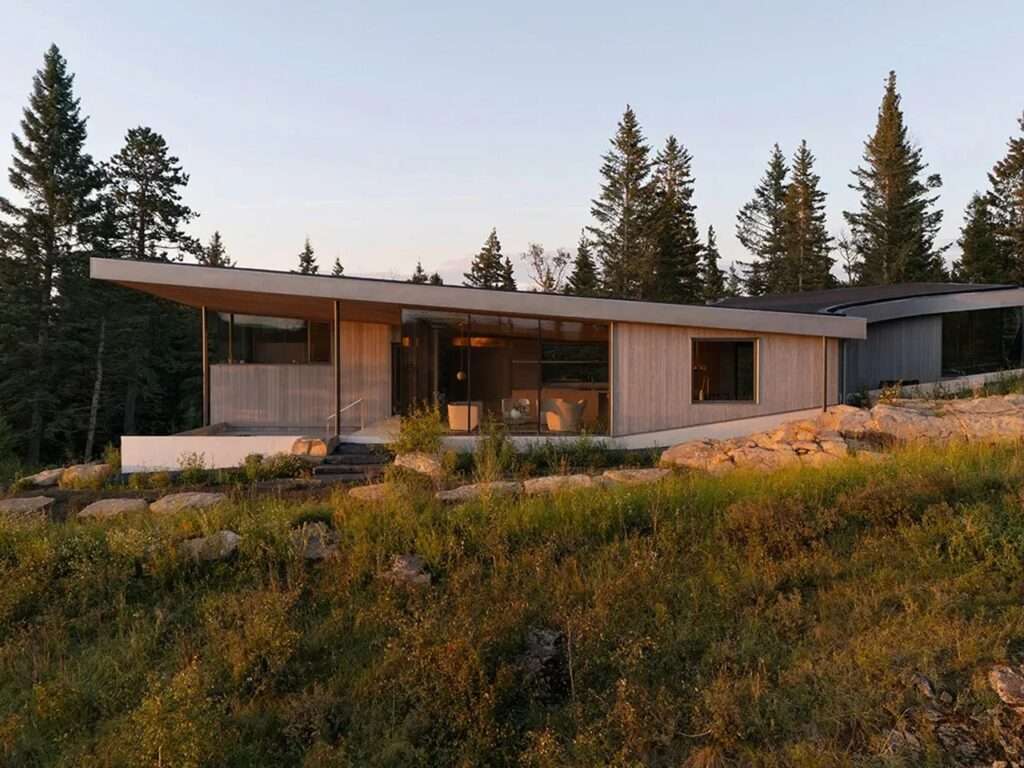 Panoramic exterior view of Cut Out House at sunset showcasing the low-profile architectural massing along a rocky ridge.