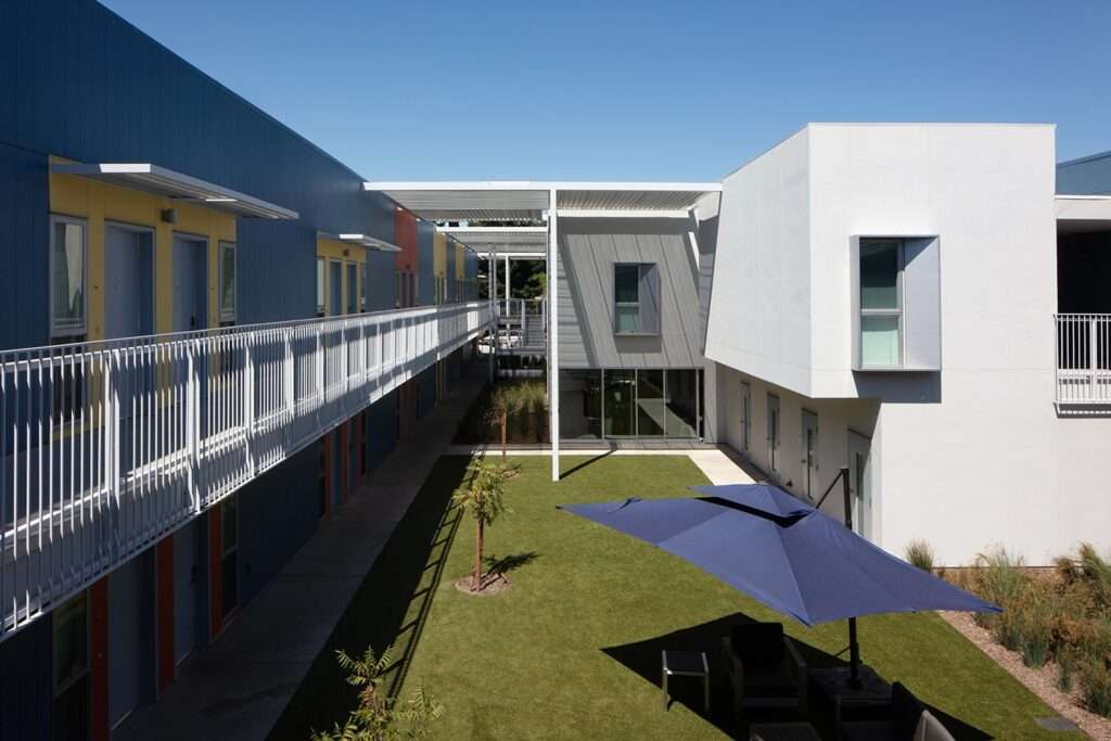 Spacious concrete patio courtyard at Northview Apartments with residents sitting at outdoor tables under dark blue umbrellas.