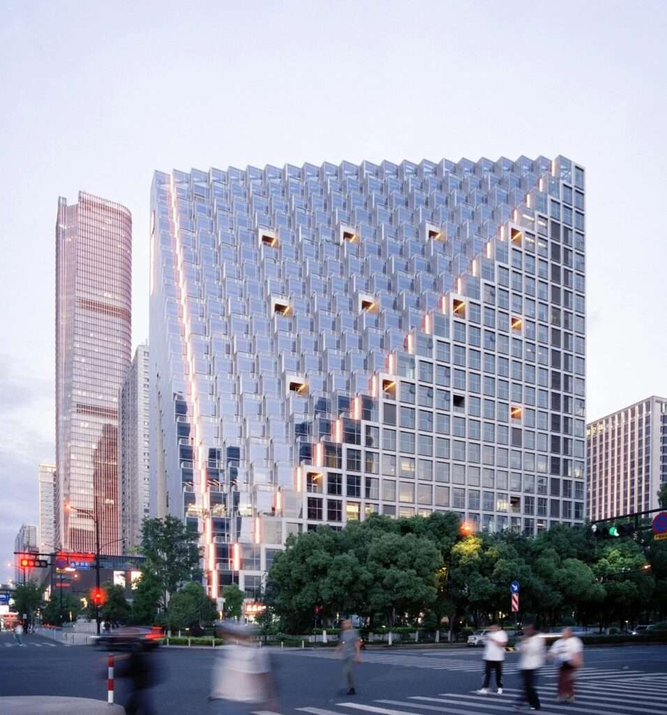Street level wide shot of the Hangzhou Prism building showcasing its entire pixelated gridded facade at an urban intersection.