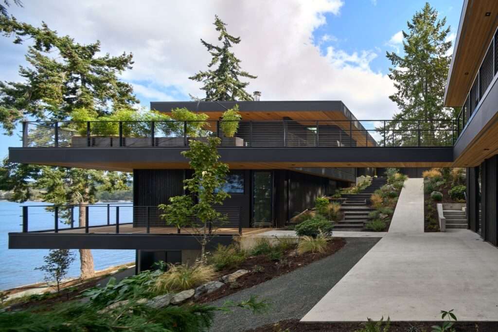 Elevated structural bridge connecting two main volumes of the Layer House over a sloped terrain.