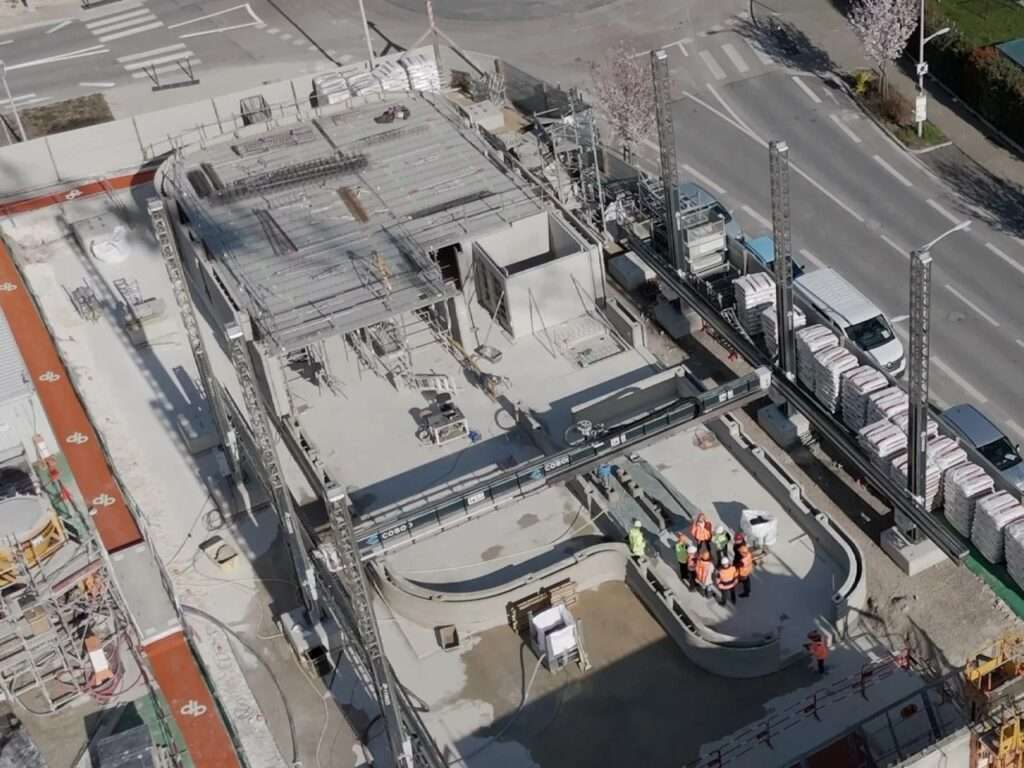 High-angle drone photograph of the ViliaSprint2 construction site showing the large-scale PERI 3D printing gantry system active over the building footprint.