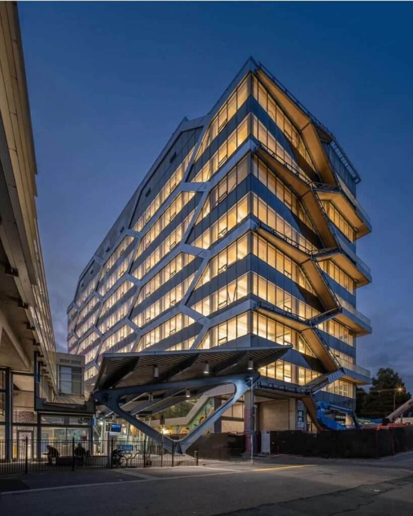 View of The Hive building exterior with a focus on the structural glulam grid and entrance canopy at twilight.