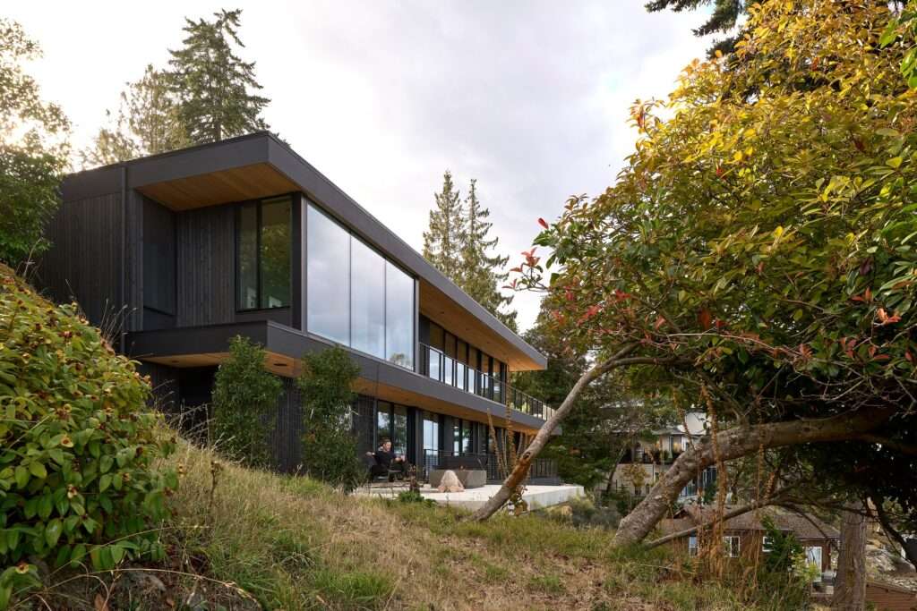 Exterior terrace with a hot tub and fire feature overlooking the coastal slope and forest.