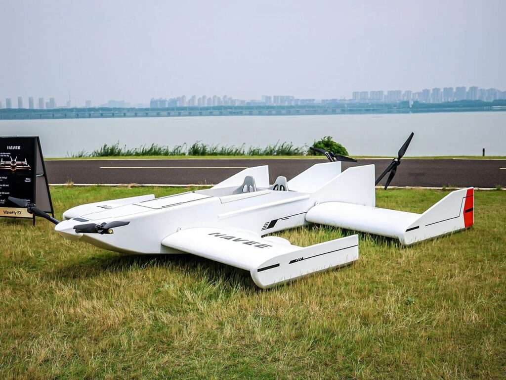 Full side view of the Navee WaveFly 5X showcased on a grassy field, highlighting its multi-wing design, open cockpit, and informational display sign.