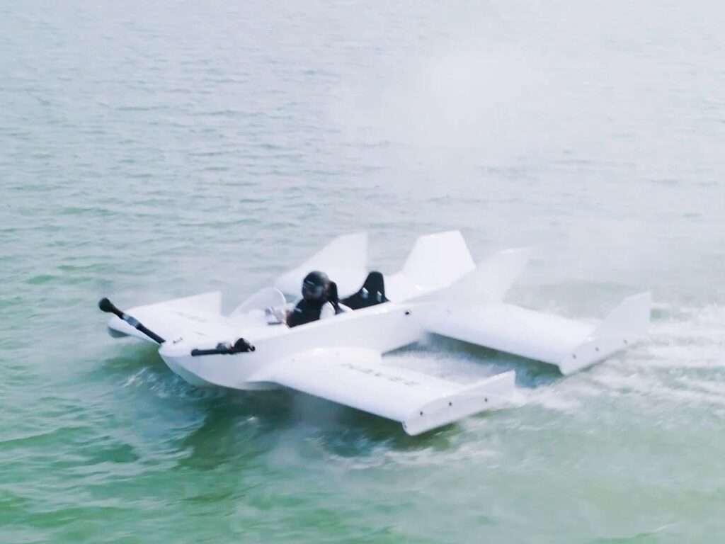 Diagonal high-angle view of the Navee WaveFly 5X executing a fast turn on the water, kicking up a light mist of spray around its aerodynamic wings.