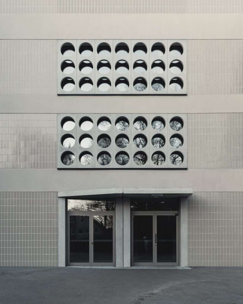 Exterior facade showing repetitive circular windows and double glass entrance doors.