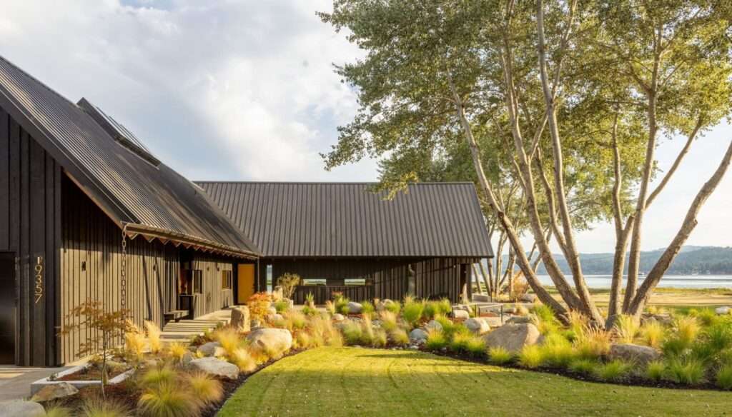 Day's Inlet House exterior showing the dark vertical wood cladding and gabled roofs facing a scenic coastal bay.