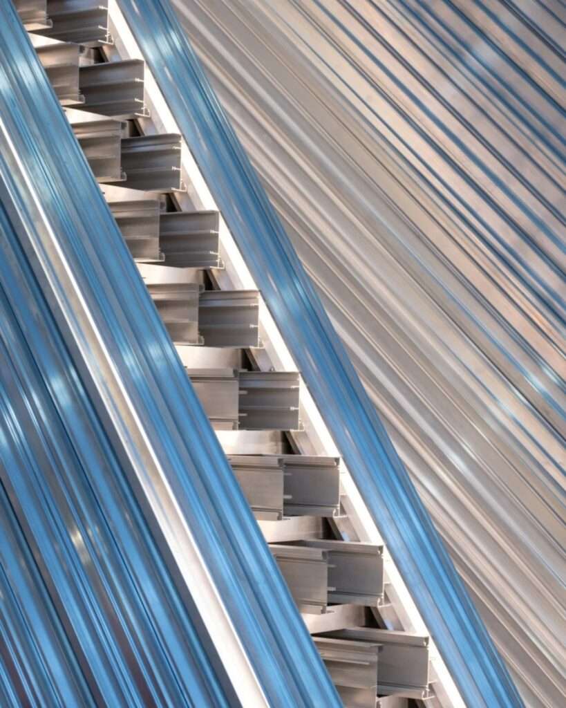 Close-up macro photograph showing the raw, unvarnished profile cuts of interlocking modular aluminum sections stacked diagonally with exposed industrial hardware.