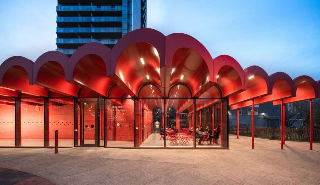 The O-day'min Park Pavilion illuminated at twilight, glowing as a lantern in the urban landscape of Edmonton's Warehouse Campus.