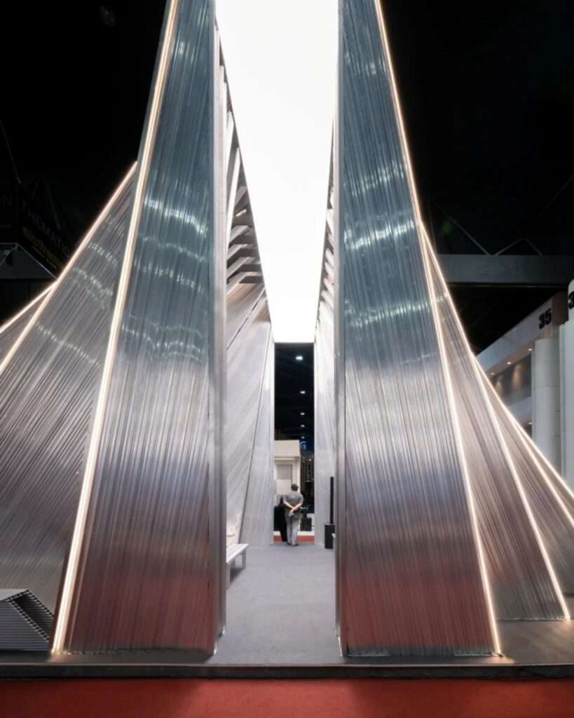 Symmetrical eye-level entry viewpoint of the UNFOLD Pavilion with vertical illuminated strip lights flanking a narrow central path that reveals an internal visitor.