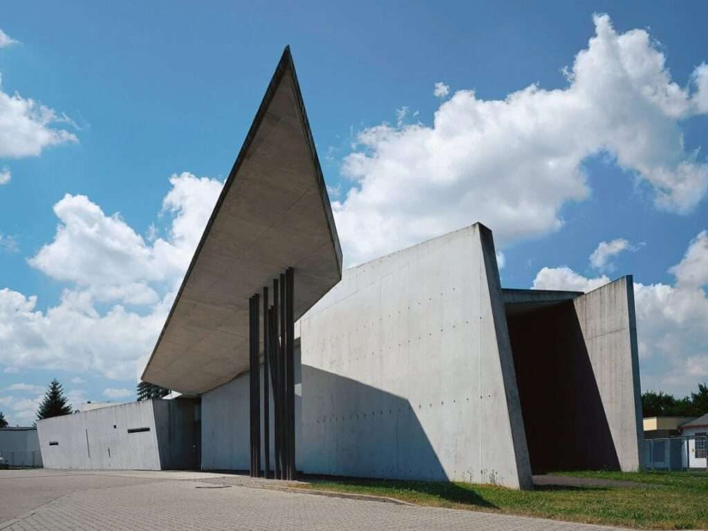 Angular concrete roof canopy supported by thin tilted steel columns at the entrance of Vitra Fire Station.