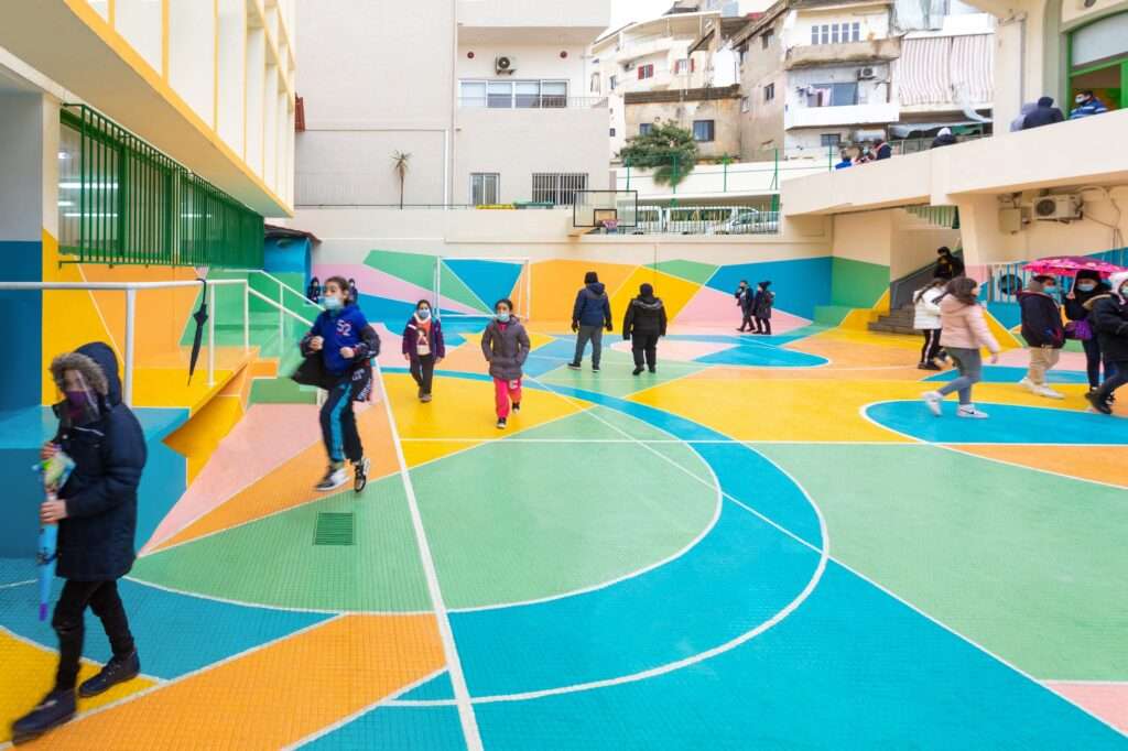 Children playing in a vibrant, colorfully painted school playground in Beirut.