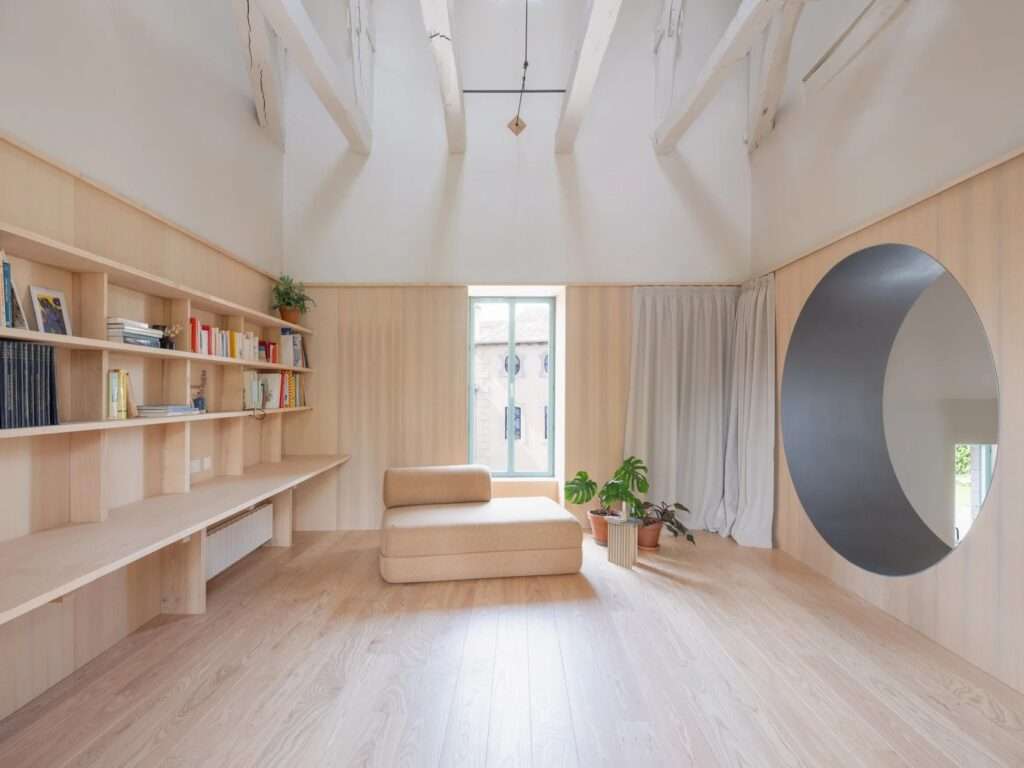 Modern kitchen and dining space with polished concrete floors, steel-framed open shelving, a wooden dining table, and a large arched glass sliding door opening to the patio.