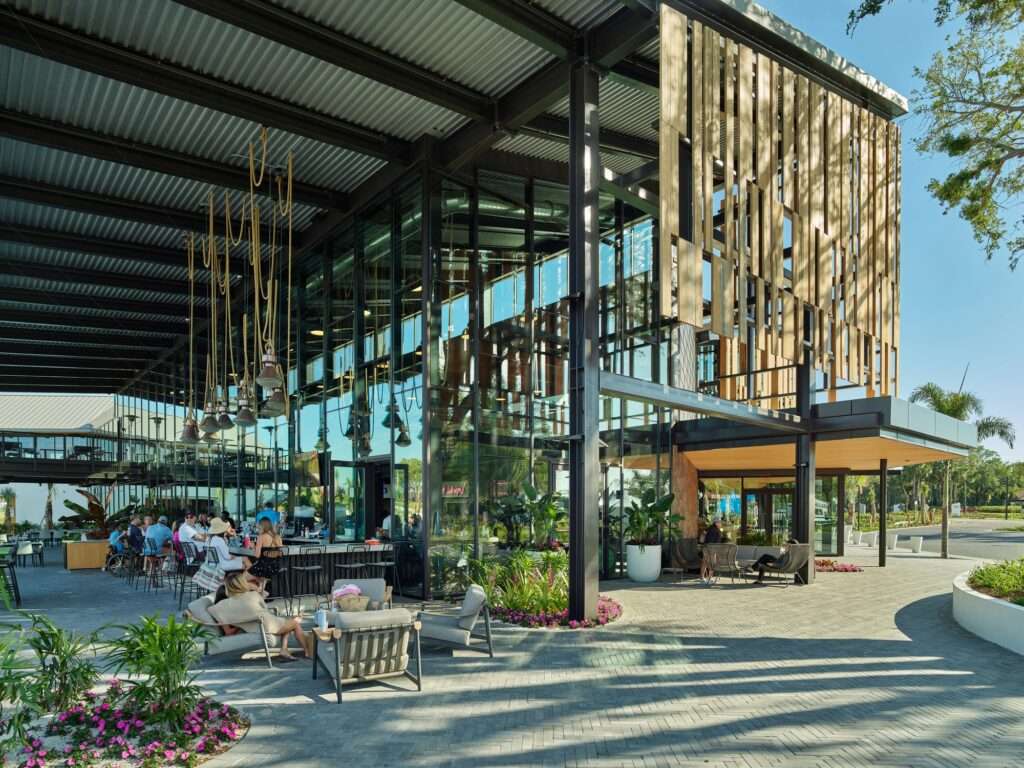 Ground-level view of the integrated indoor-outdoor bar and lounge area at the Evermore resort social hub.
