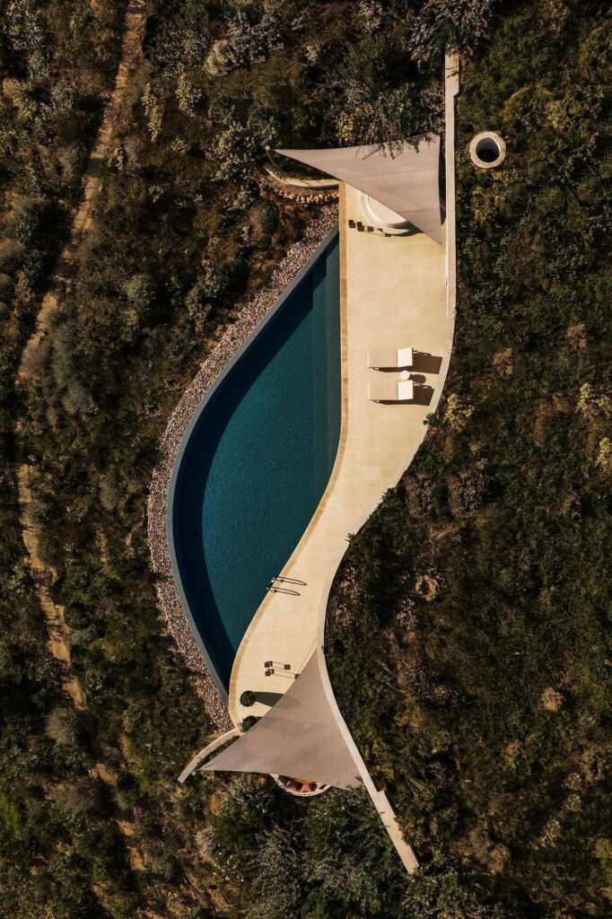 Symmetrical overhead drone view of a subterranean dual villa entry path, green planted roofs, and private plunge pools.