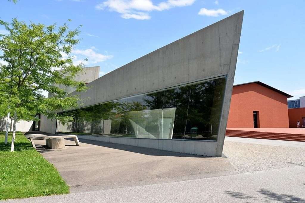 Sharp angular exposed concrete wall with a large glass window pane at Vitra Fire Station designed by Zaha Hadid in Weil am Rhein Germany.