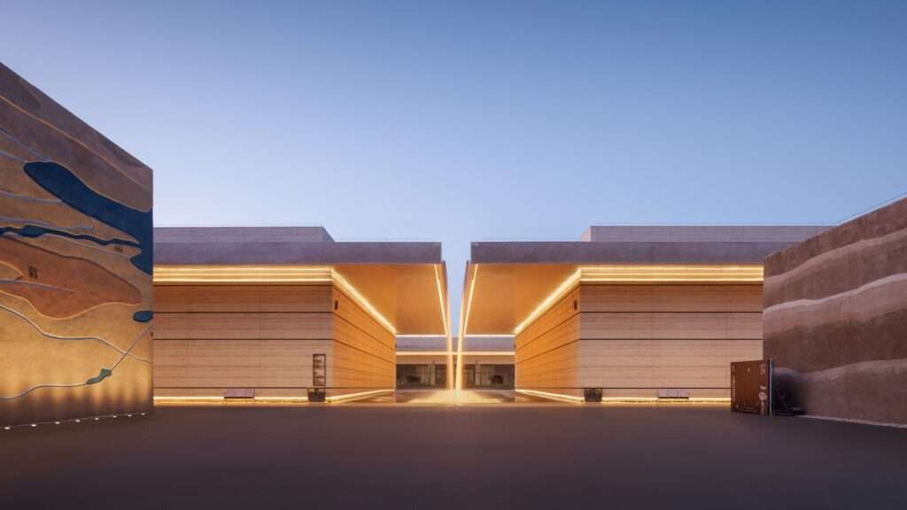 Submerged museum entrance plaza at dusk with linear warm LED lighting emphasizing massive cantilevered roof planes and textured concrete walls.