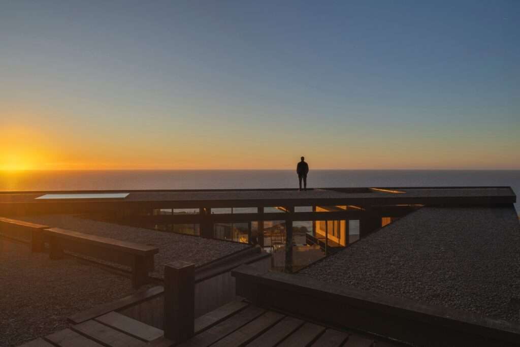 Person standing on the rooftop of Matanzas Beach House during sunset overlooking the ocean.