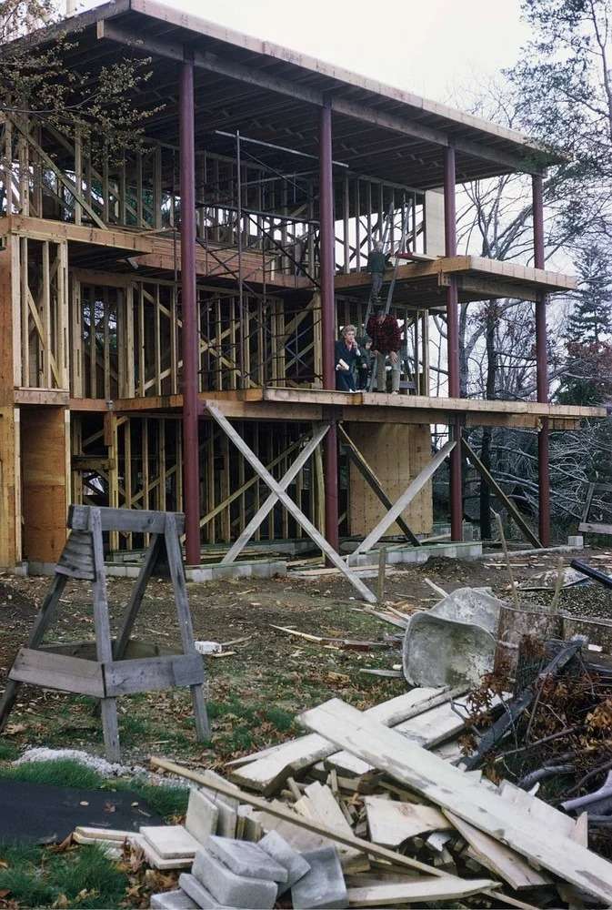 Exterior view of Richard Meier's Smith House showing the white geometric, vertical massing and expansive glass facade overlooking a grassy slope.