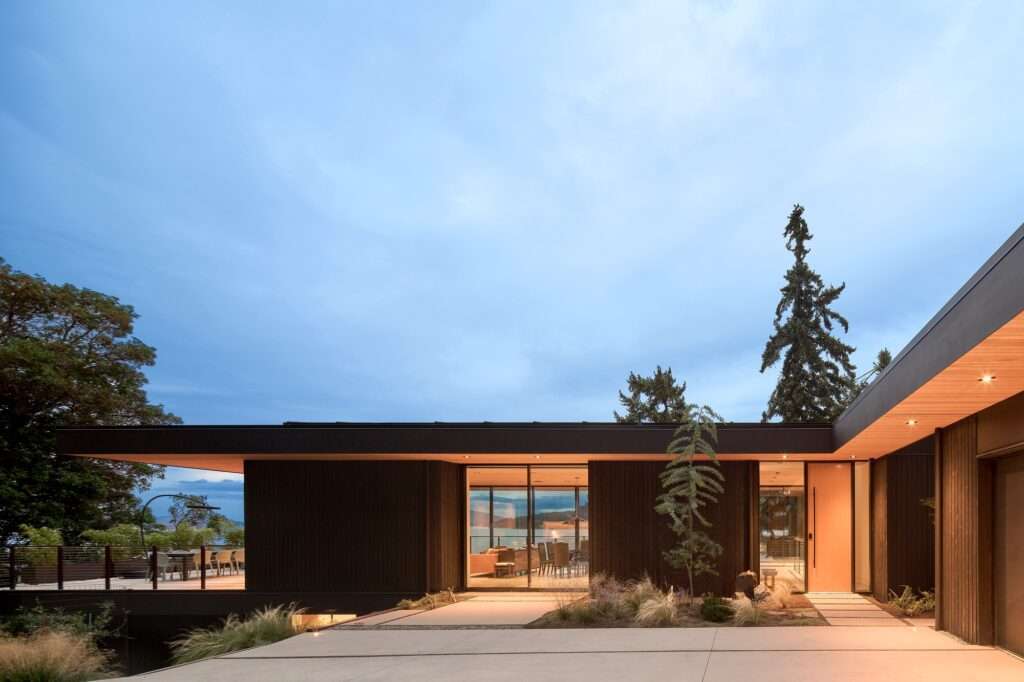 View of the Layer House exterior architecture at dusk, showing the house integrated into the sloped site.