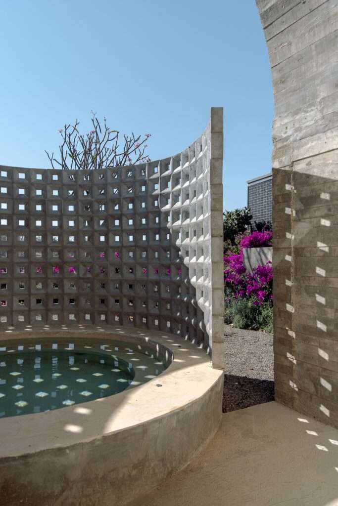 Perspective view of a raw concrete barrel vault at Casa Cielo overlooking the Sierra Norte mountain range landscape with lavender in the foreground.