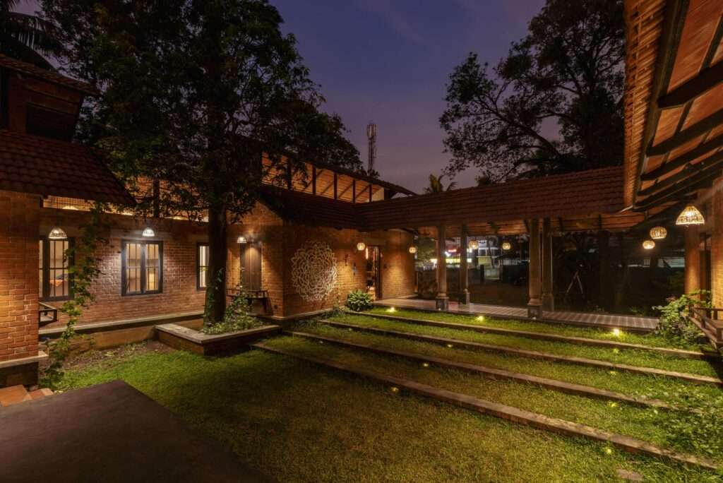 Evening view of the open courtyard and amphitheater illuminated by warm ambient lighting beneath a dark blue twilight sky.