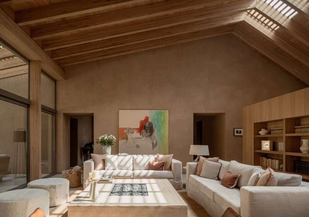 Spacious open-plan interior showing the living room and dining area under a slatted timber ceiling with soft filtered sunlight.