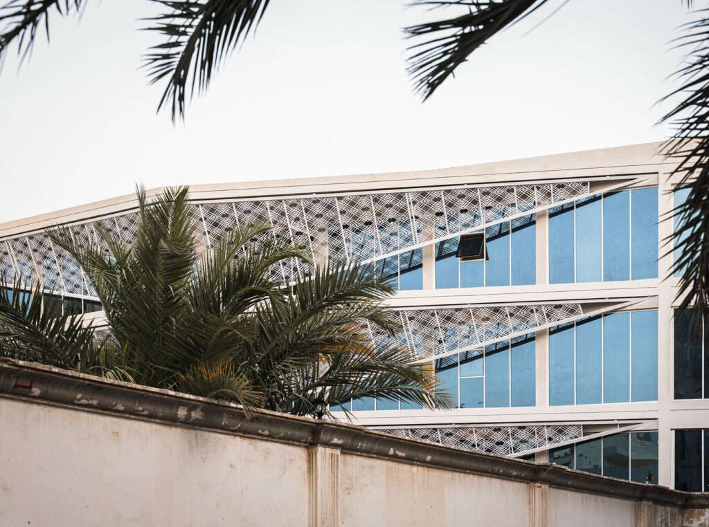 Partial view of the Indonesian Consulate facade in Jeddah framed by palm tree leaves.