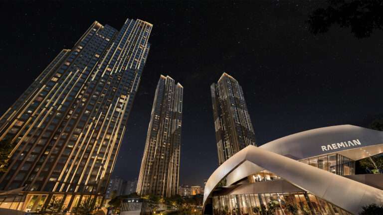 Night view of illuminated high-rise residential towers and a curved pavilion with Raemian signage under a starry sky.