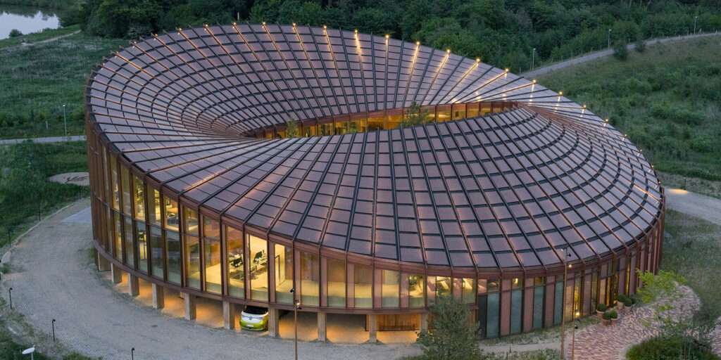 Aerial view of a circular office building with an undulating roof covered in solar panels and a central courtyard.