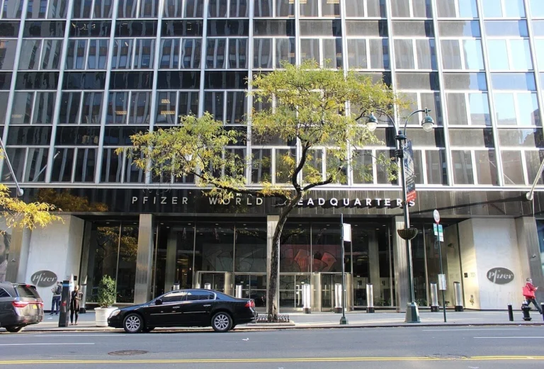Street-level view of the glass and steel facade of the former Pfizer World Headquarters building entrance.