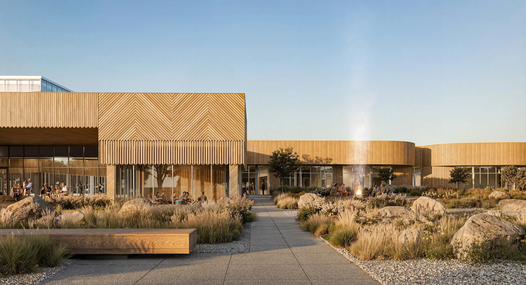 Exterior view of a wood-clad wellness center with native plantings and stone elements in the foreground.