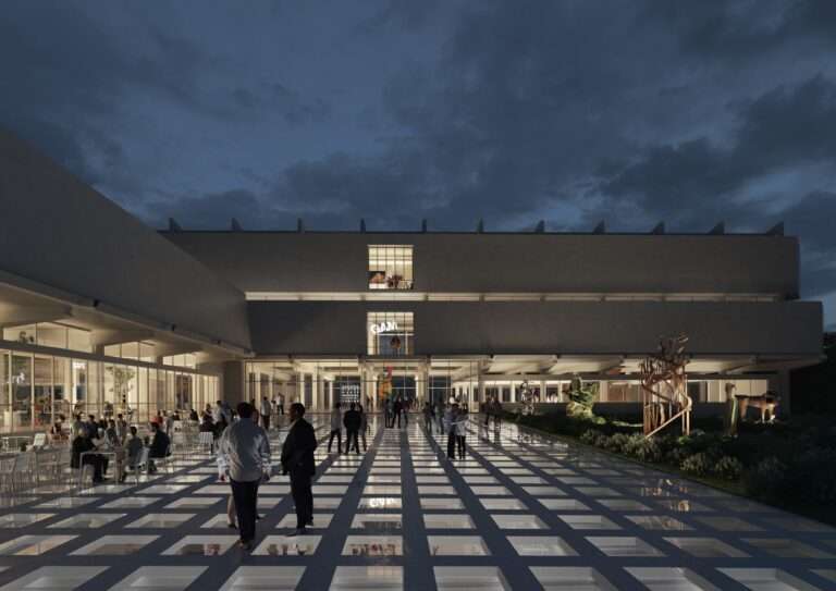 A modern building facade at night with a public plaza featuring square ground openings and a cafe area.