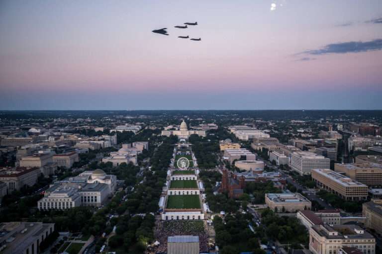Aerial view of the National Mall with military jets flying over the fairgrounds toward the Capitol.