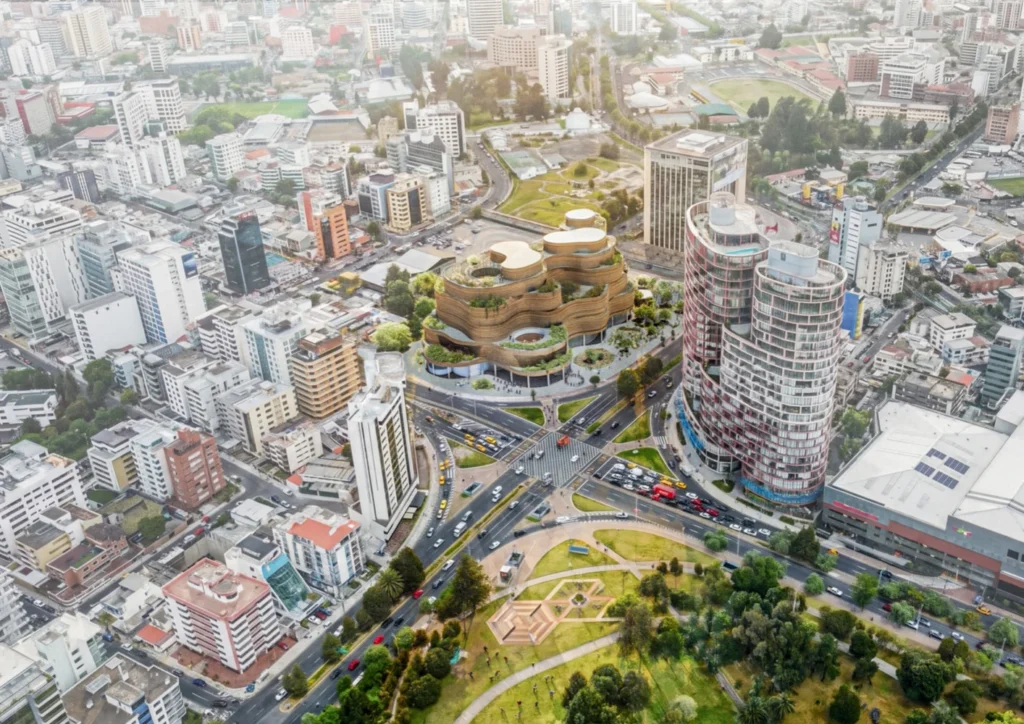 Aerial view showing a terraced organic building situated at a major urban intersection near a park.