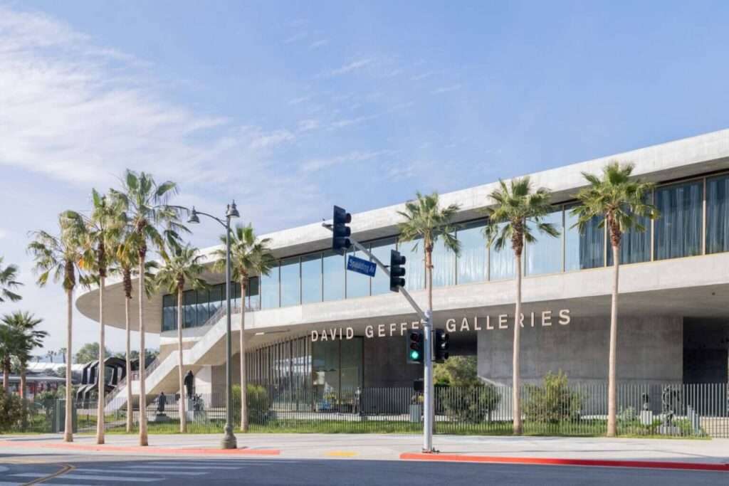 A daytime exterior shot from across a street showing a horizontal concrete building with 'DAVID GEFFEN GALLERIES' signage, flanked by palm trees.
