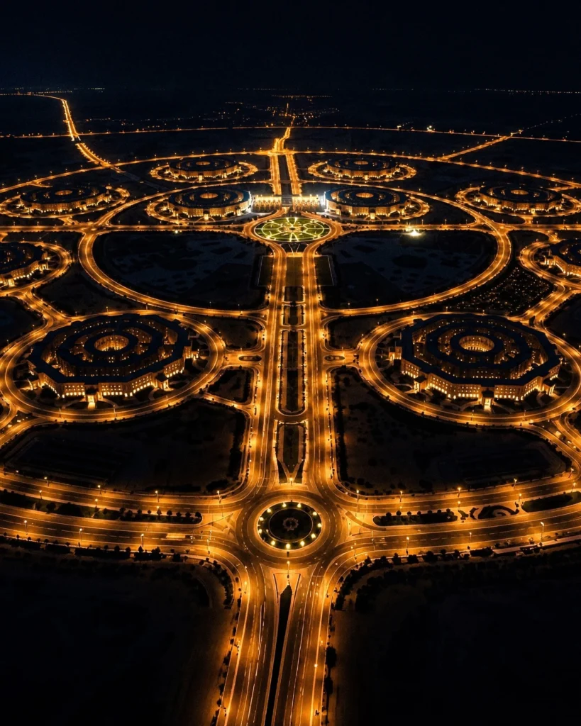 Night aerial shot showcasing the illuminated circular roadways and octagonal buildings within the military complex.