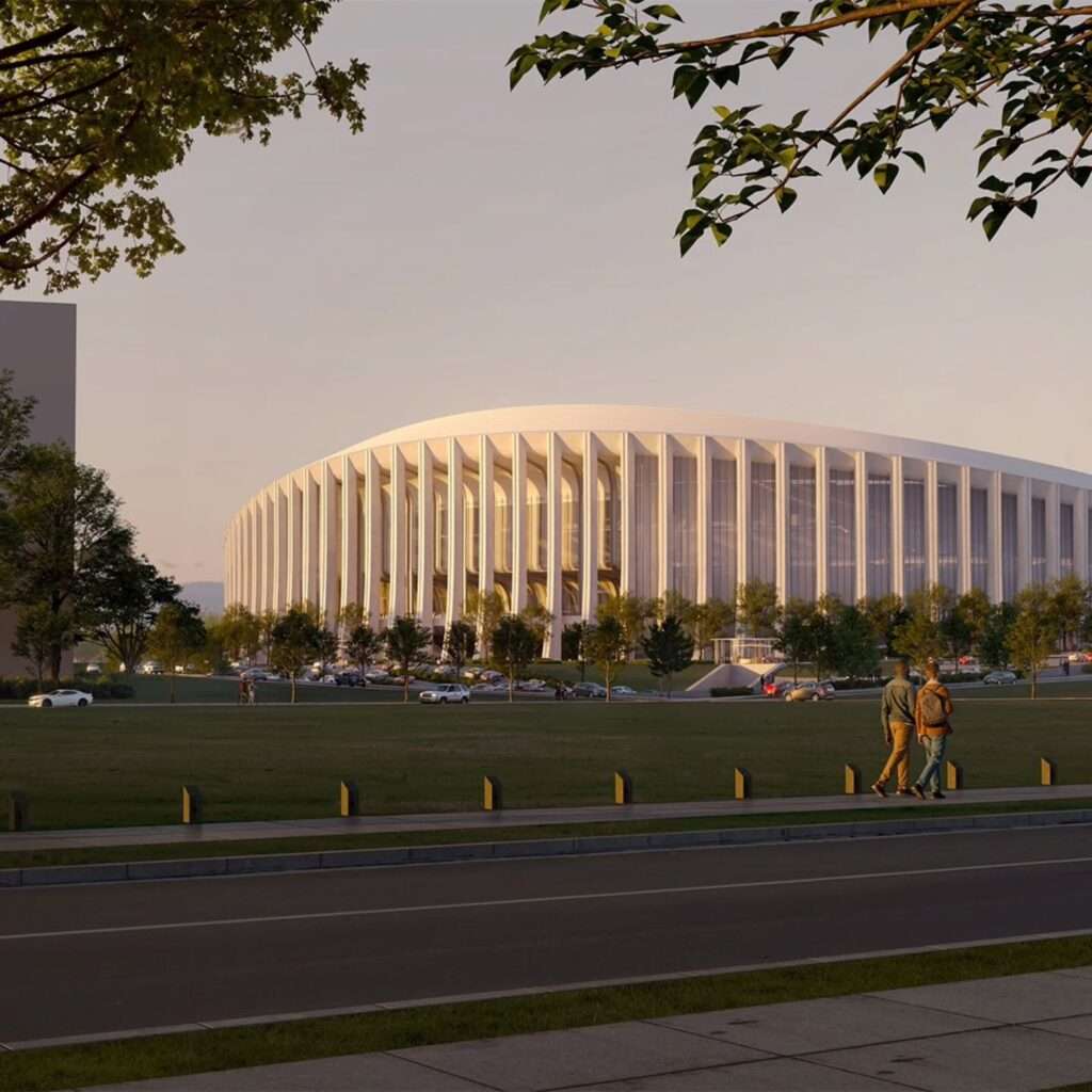 Pedestrian perspective showing vertical concrete columns along the side facade during twilight.