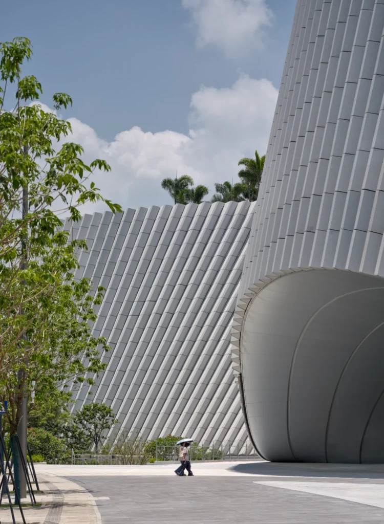 Close-up of textured sloped granite cladding panels curving into an arched building entrance.